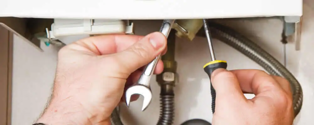 Boiler repair technician tightening pipe fittings and connections in Redding, CA