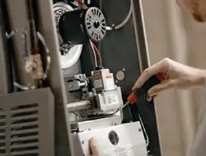 Furnace repair technician inspecting internal components and wiring in Redding, CA