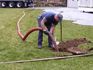 Septic pumping technician servicing a residential septic tank with a vacuum hose in Redding, CA