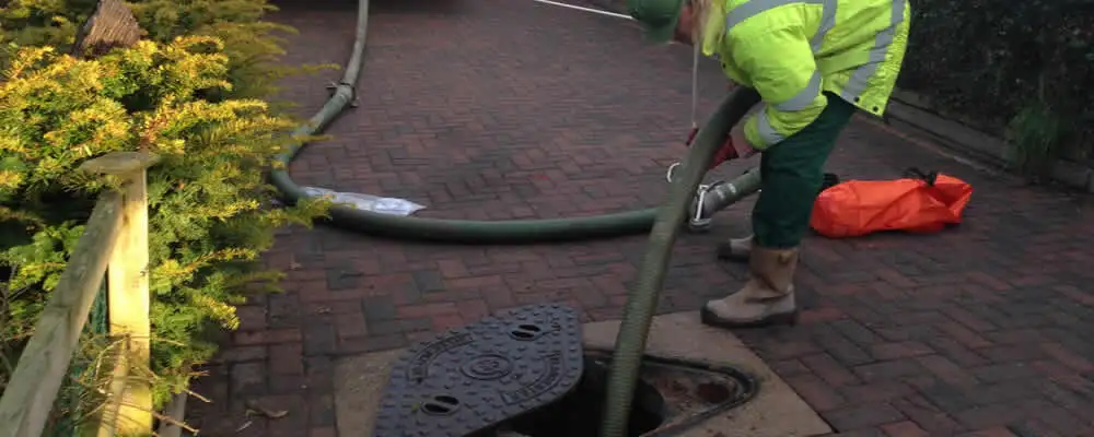 Septic tank cleaning technician servicing a septic tank with a vacuum hose in Redding, CA