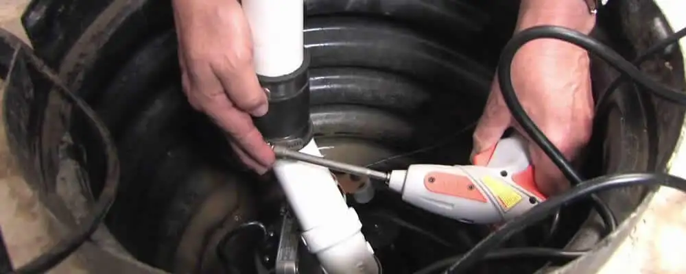 Sump pump installation technician connecting PVC discharge piping in Redding, CA