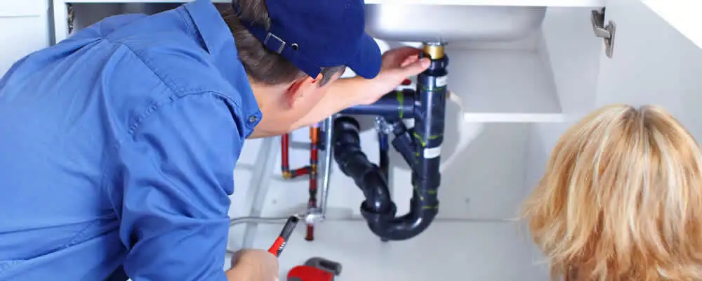 Plumber repairing under-sink drain pipes and fittings in Redding, CA